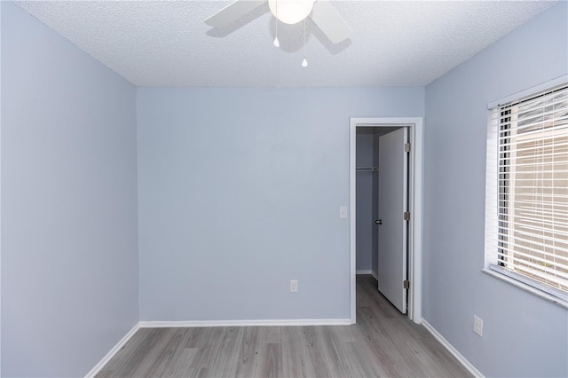 unfurnished room with a ceiling fan, a textured ceiling, baseboards, and wood finished floors