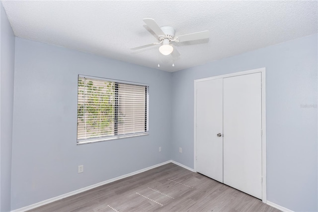 unfurnished bedroom with baseboards, a ceiling fan, wood finished floors, a textured ceiling, and a closet