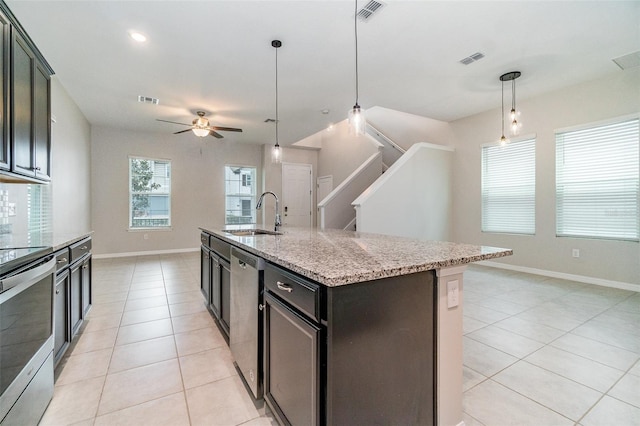 kitchen featuring a center island with sink, ceiling fan, stainless steel appliances, hanging light fixtures, and sink