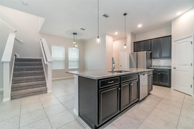 kitchen with pendant lighting, sink, appliances with stainless steel finishes, an island with sink, and light tile patterned floors