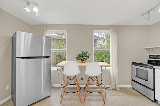 kitchen featuring white cabinets, stainless steel appliances, a wealth of natural light, and light tile patterned floors