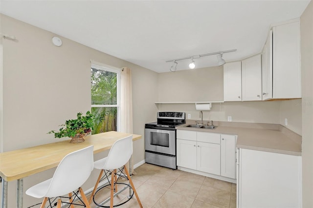 kitchen featuring sink, stainless steel electric range oven, light tile patterned floors, and white cabinetry