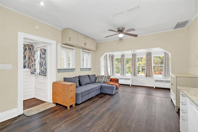 living room featuring ornamental molding, dark wood-type flooring, a wealth of natural light, and ceiling fan