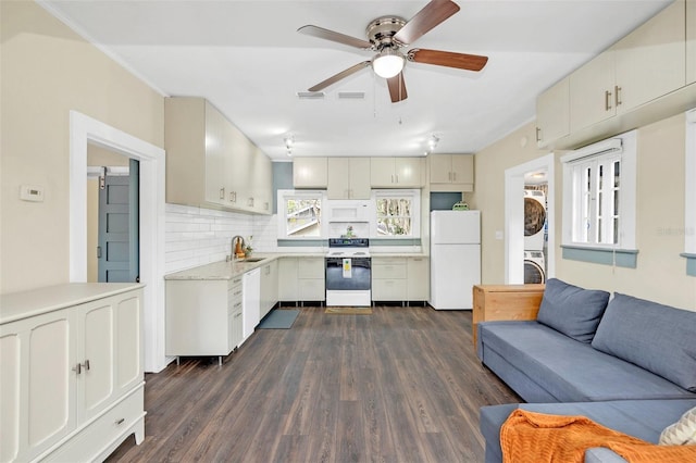 kitchen featuring white appliances, dark wood-type flooring, sink, backsplash, and stacked washer and dryer