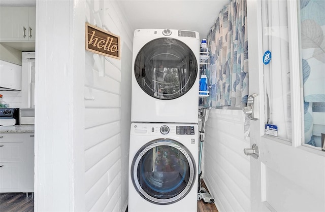 laundry room featuring dark hardwood / wood-style flooring and stacked washer and dryer