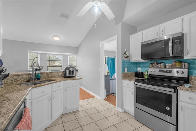 kitchen featuring lofted ceiling, white cabinetry, stainless steel appliances, sink, and light tile patterned flooring