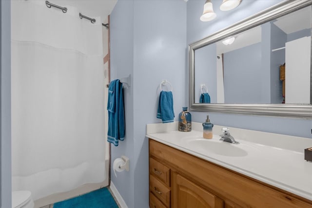 bathroom featuring toilet, vanity, and walk in shower