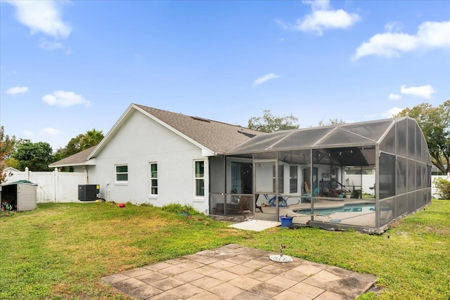 rear view of property featuring glass enclosure, cooling unit, a yard, a fenced in pool, and a patio