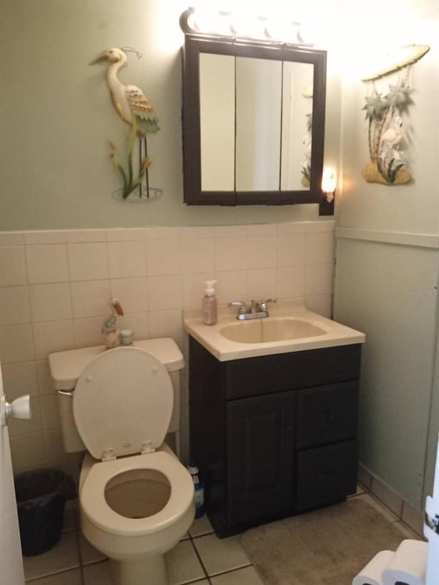 bathroom featuring toilet, tile patterned flooring, tile walls, and vanity