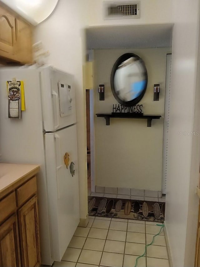 interior space with light tile patterned flooring and white fridge