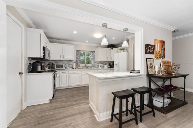 kitchen with crown molding, white cabinetry, light hardwood / wood-style flooring, hanging light fixtures, and stainless steel appliances