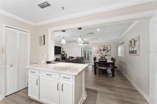 kitchen with white cabinetry, light wood-type flooring, ornamental molding, and a kitchen island