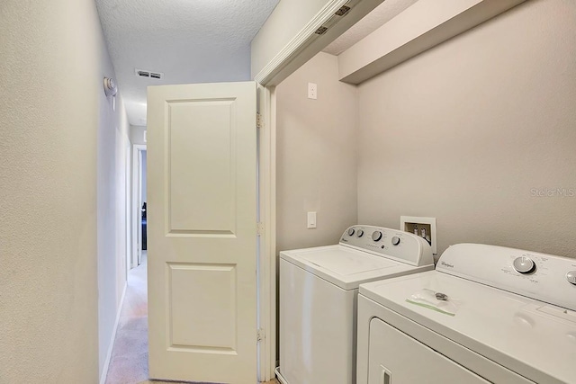 clothes washing area featuring washing machine and clothes dryer and a textured ceiling