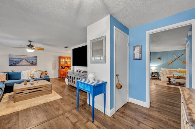 living room featuring ceiling fan, a textured ceiling, and hardwood / wood-style flooring