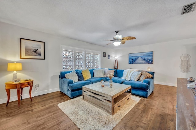 living room with hardwood / wood-style flooring, a textured ceiling, and ceiling fan