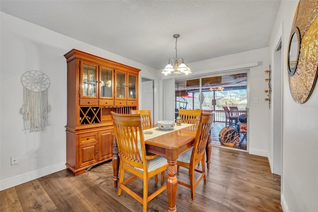 dining space featuring a textured ceiling, wood-type flooring, and a notable chandelier