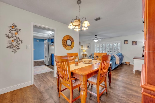 dining room with dark wood-type flooring and ceiling fan with notable chandelier