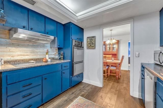 kitchen with appliances with stainless steel finishes, decorative backsplash, blue cabinets, a chandelier, and crown molding