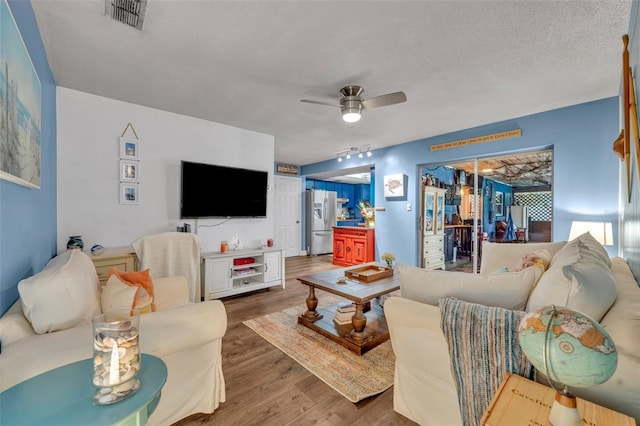 living room featuring ceiling fan, a textured ceiling, track lighting, and hardwood / wood-style flooring