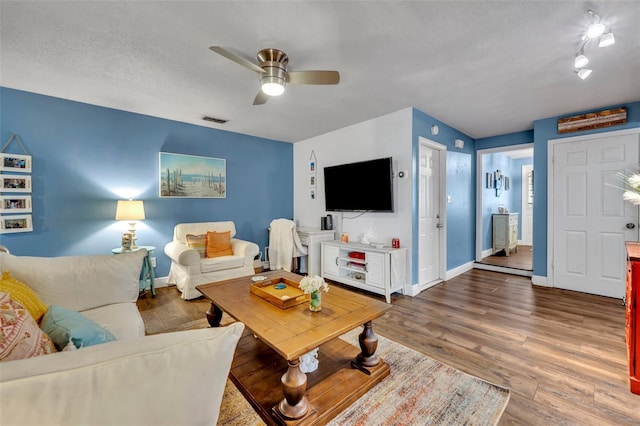 living room with dark wood-type flooring, ceiling fan, and a textured ceiling