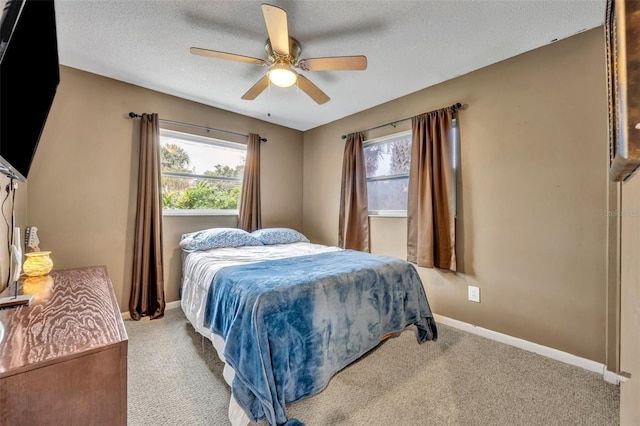 carpeted bedroom featuring ceiling fan and a textured ceiling