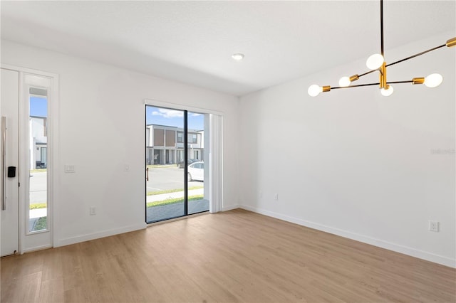 unfurnished room featuring light wood-type flooring and a notable chandelier