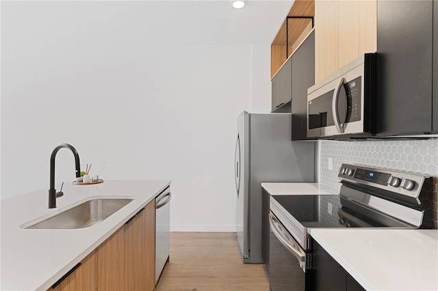 kitchen featuring stainless steel appliances, light hardwood / wood-style flooring, tasteful backsplash, and sink