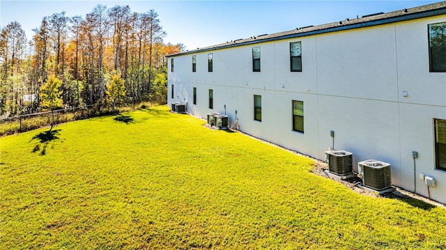 exterior space with central AC unit and a lawn