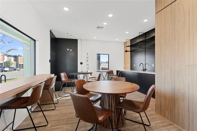 dining area featuring a wealth of natural light, sink, and light hardwood / wood-style flooring