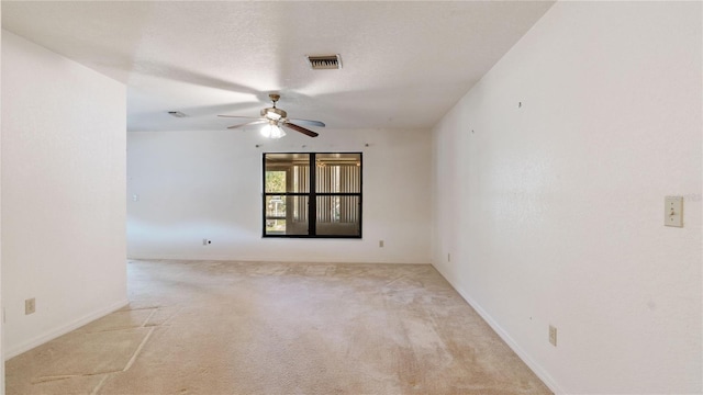 empty room featuring ceiling fan, light carpet, and a textured ceiling