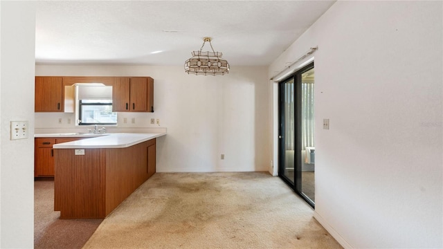 kitchen featuring hanging light fixtures, light carpet, sink, and kitchen peninsula