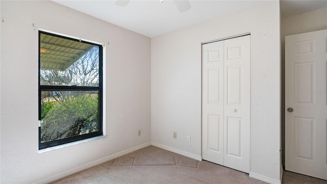 unfurnished bedroom with ceiling fan, a closet, and carpet flooring