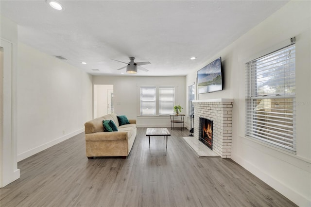 living room featuring a brick fireplace, ceiling fan, and hardwood / wood-style floors