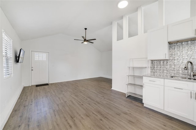 kitchen with sink, backsplash, white cabinets, and vaulted ceiling