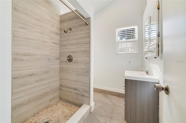 bathroom with tile patterned floors, a tile shower, and vanity