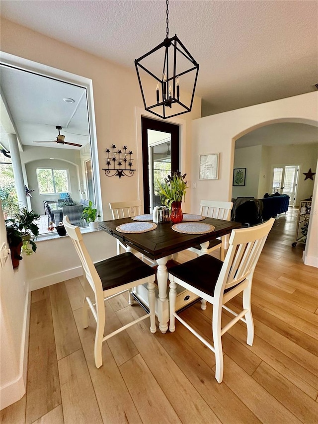 dining area featuring ceiling fan with notable chandelier, a textured ceiling, and hardwood / wood-style floors