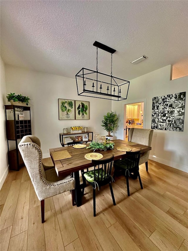 dining space featuring a textured ceiling and light wood-type flooring