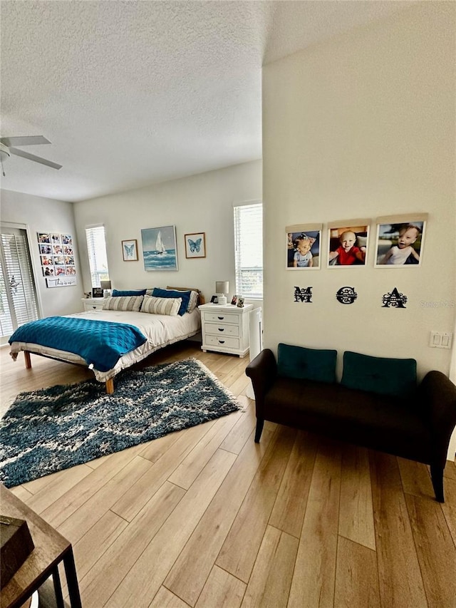 bedroom featuring ceiling fan, light hardwood / wood-style flooring, and a textured ceiling