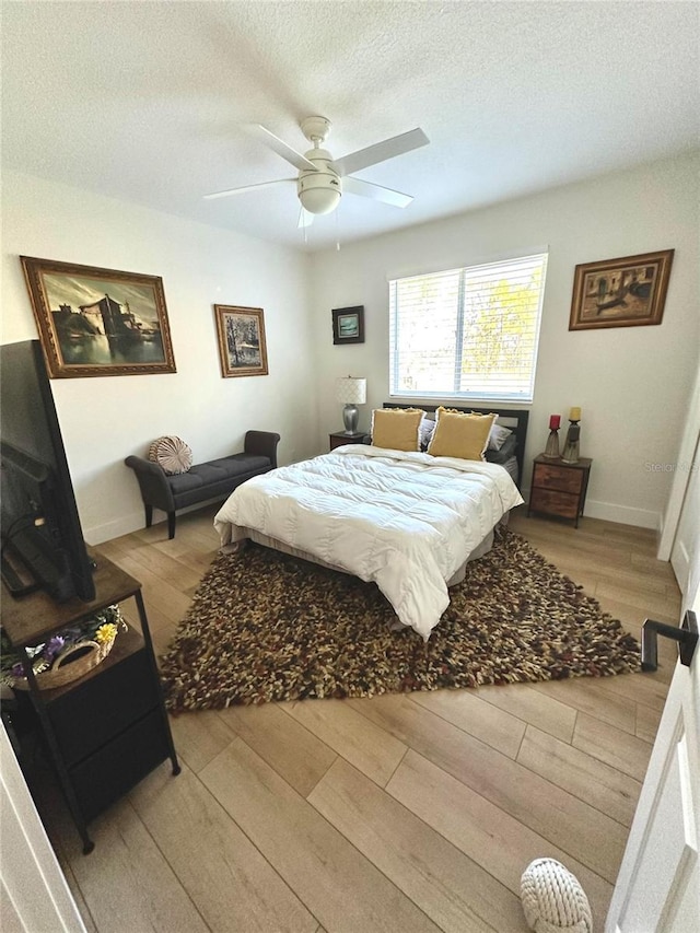 bedroom with light wood-type flooring, ceiling fan, and a textured ceiling