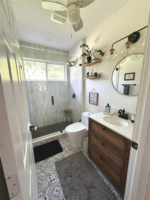 bathroom featuring a textured ceiling, a shower with door, vanity, and toilet