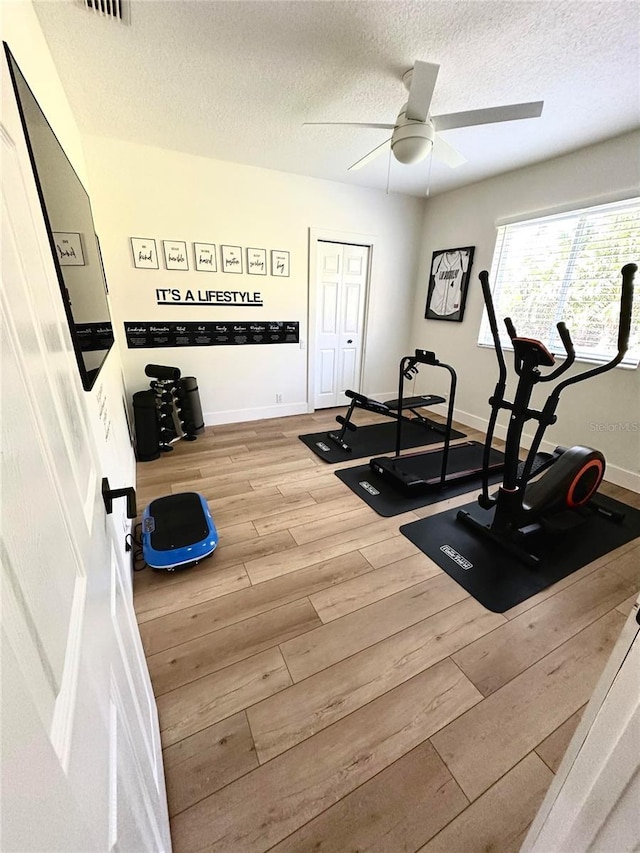 exercise room featuring a textured ceiling, ceiling fan, and light hardwood / wood-style floors