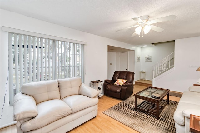 living room with hardwood / wood-style flooring, a textured ceiling, and ceiling fan