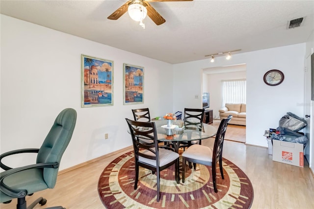 dining space with light wood-type flooring, ceiling fan, and a textured ceiling