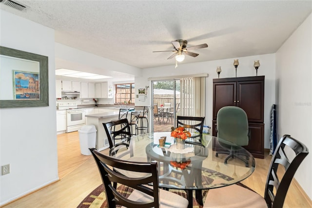 dining space featuring ceiling fan, a textured ceiling, and light wood-type flooring