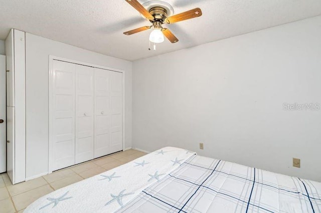 bedroom with a textured ceiling, ceiling fan, light tile patterned flooring, and a closet