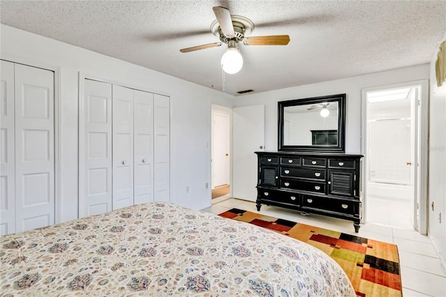 bedroom with a textured ceiling, ceiling fan, and two closets