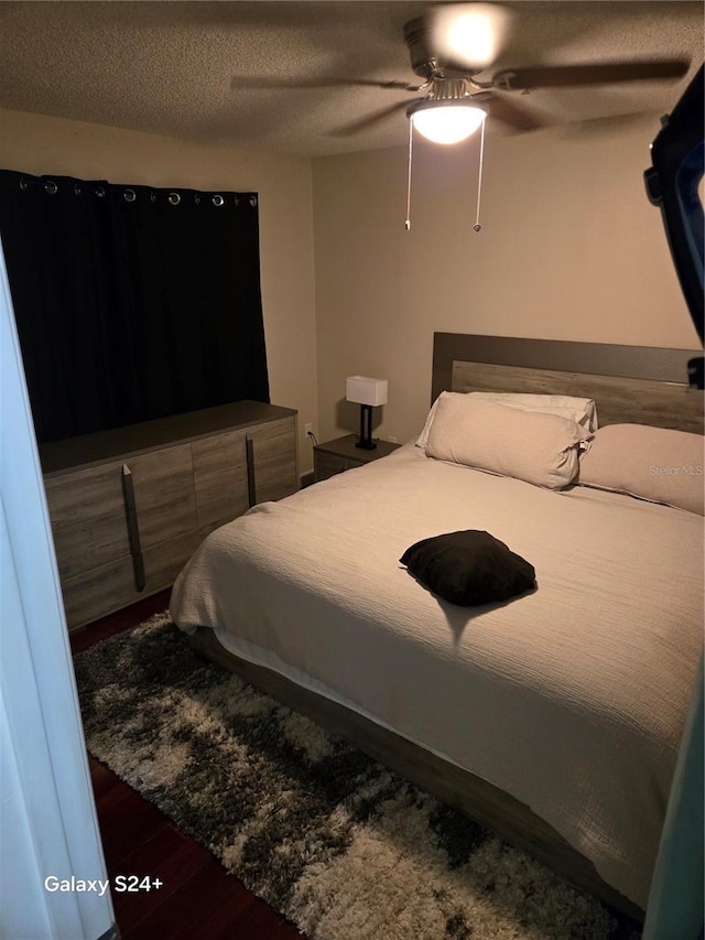 bedroom with ceiling fan, hardwood / wood-style floors, and a textured ceiling