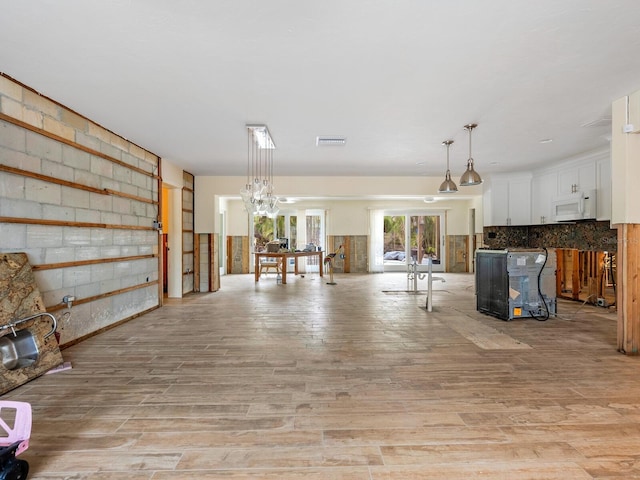 interior space featuring light wood-type flooring, white cabinetry, pendant lighting, and decorative backsplash