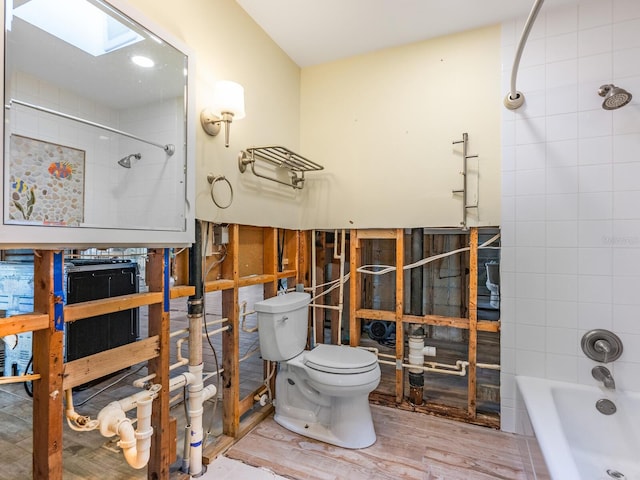 bathroom featuring toilet, a skylight, tiled shower / bath, and hardwood / wood-style floors