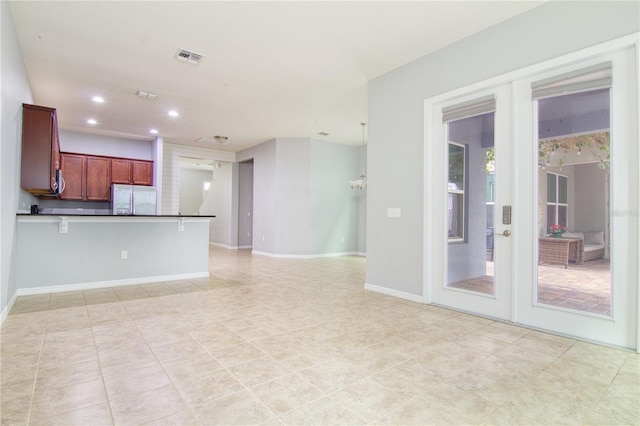 kitchen featuring french doors, light tile patterned floors, kitchen peninsula, stainless steel fridge, and a breakfast bar